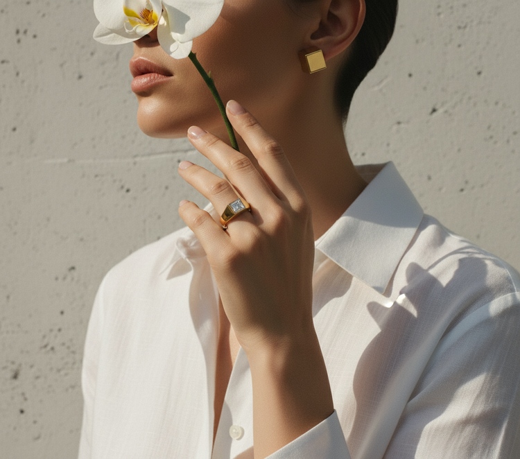 Model wearing a modern minimalist gold ring and a square geometric earring from The Architect Collection.