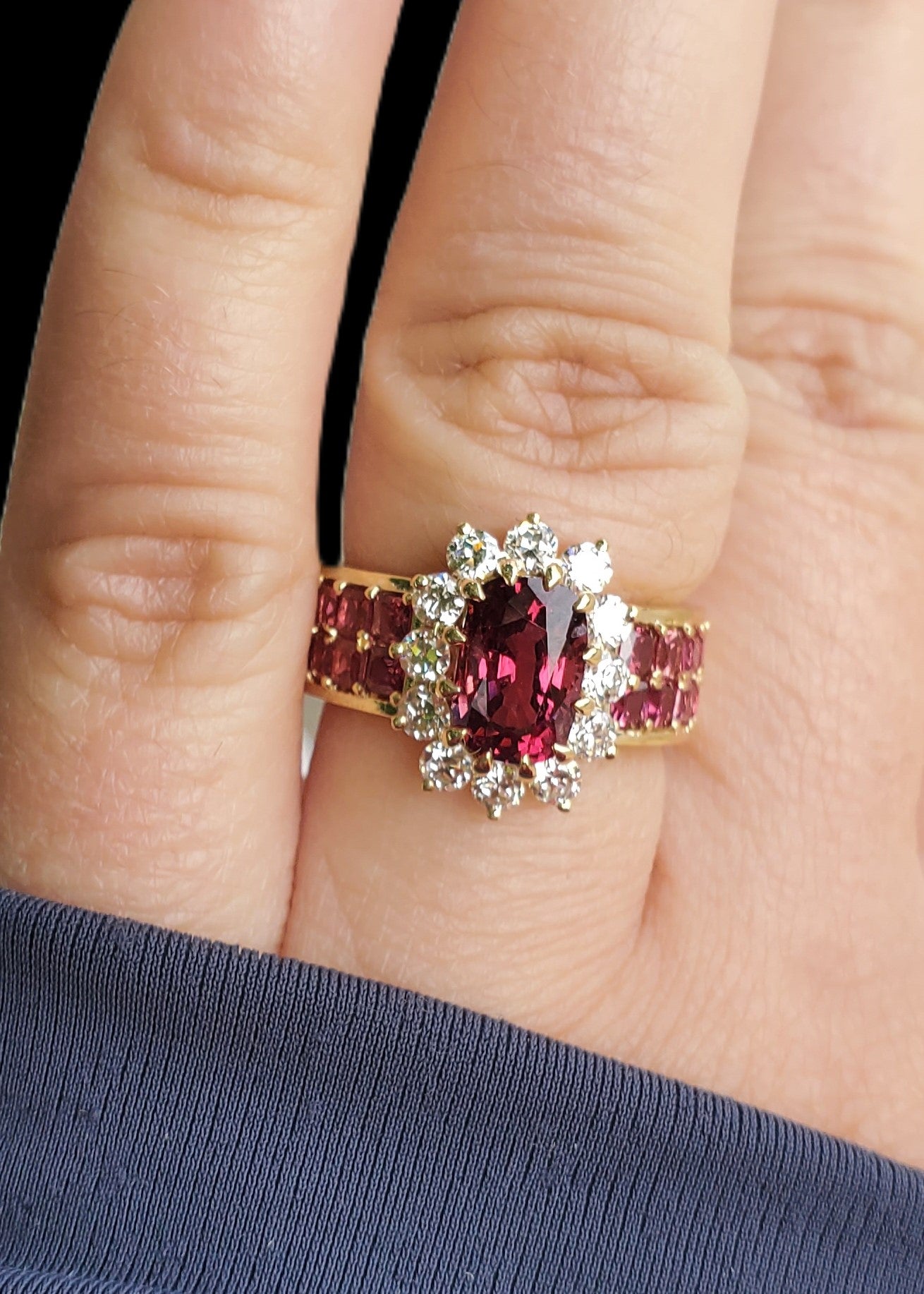 ngled view of the Crimson Bloom halo ring worn on a hand, showing the vibrant red-pink color of the spinel in natural light.