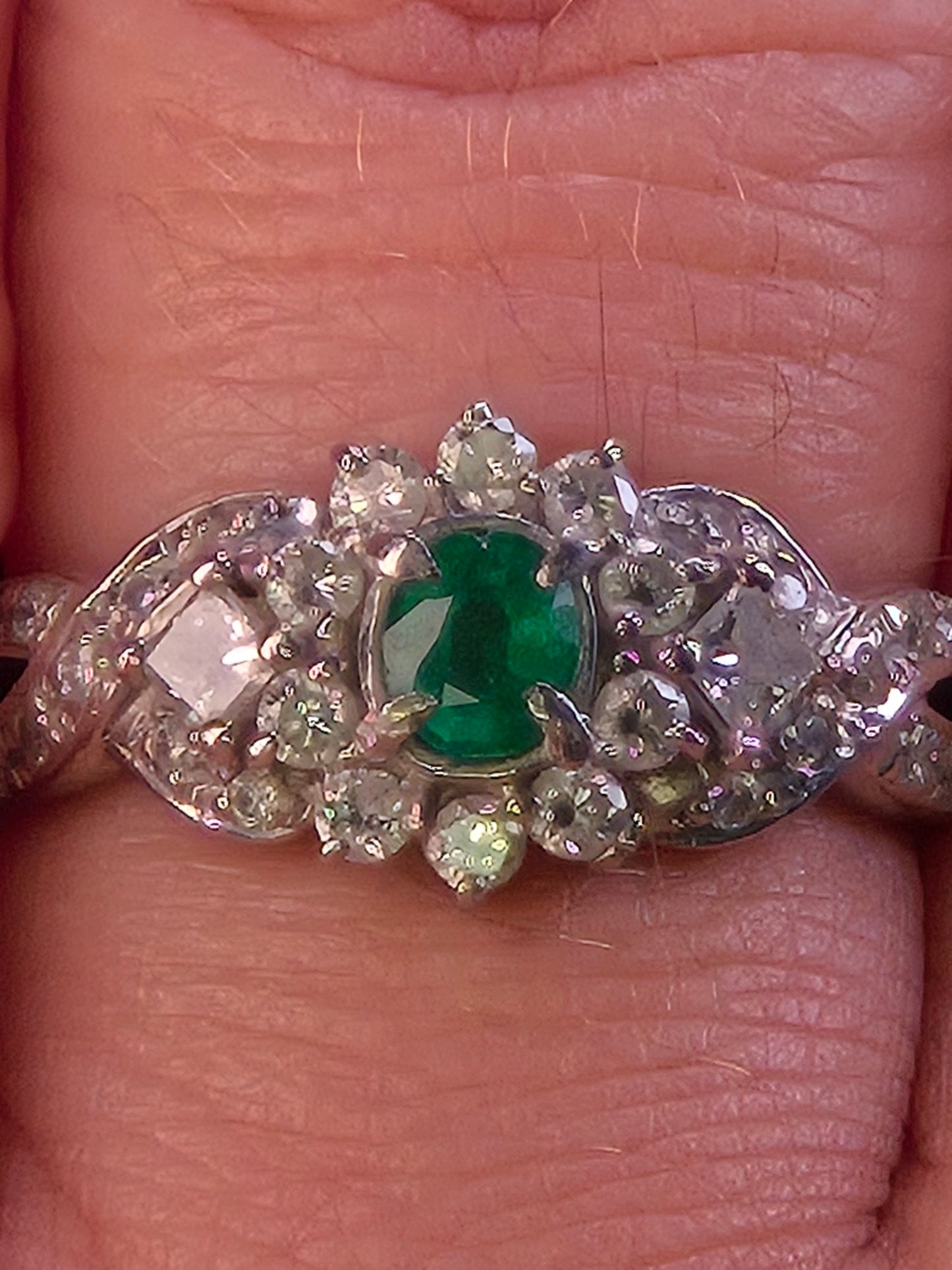 A close-up lifestyle photo of the Jardin Japonais emerald cluster ring being worn, showing the intricate details of the platinum and diamond setting.