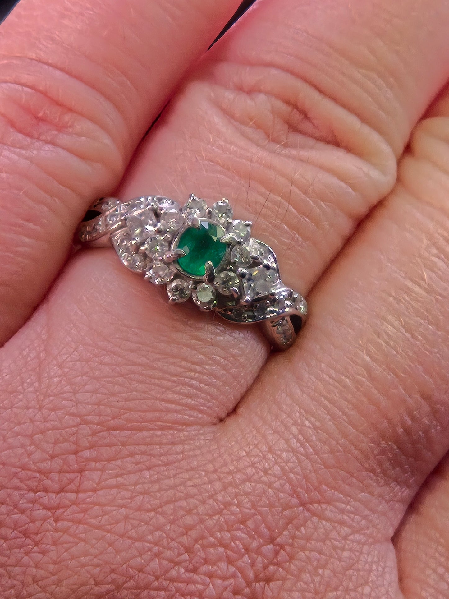Top-down view of the Jardin Japonais emerald and diamond ring worn on a hand, displaying its elegant shape and scale.