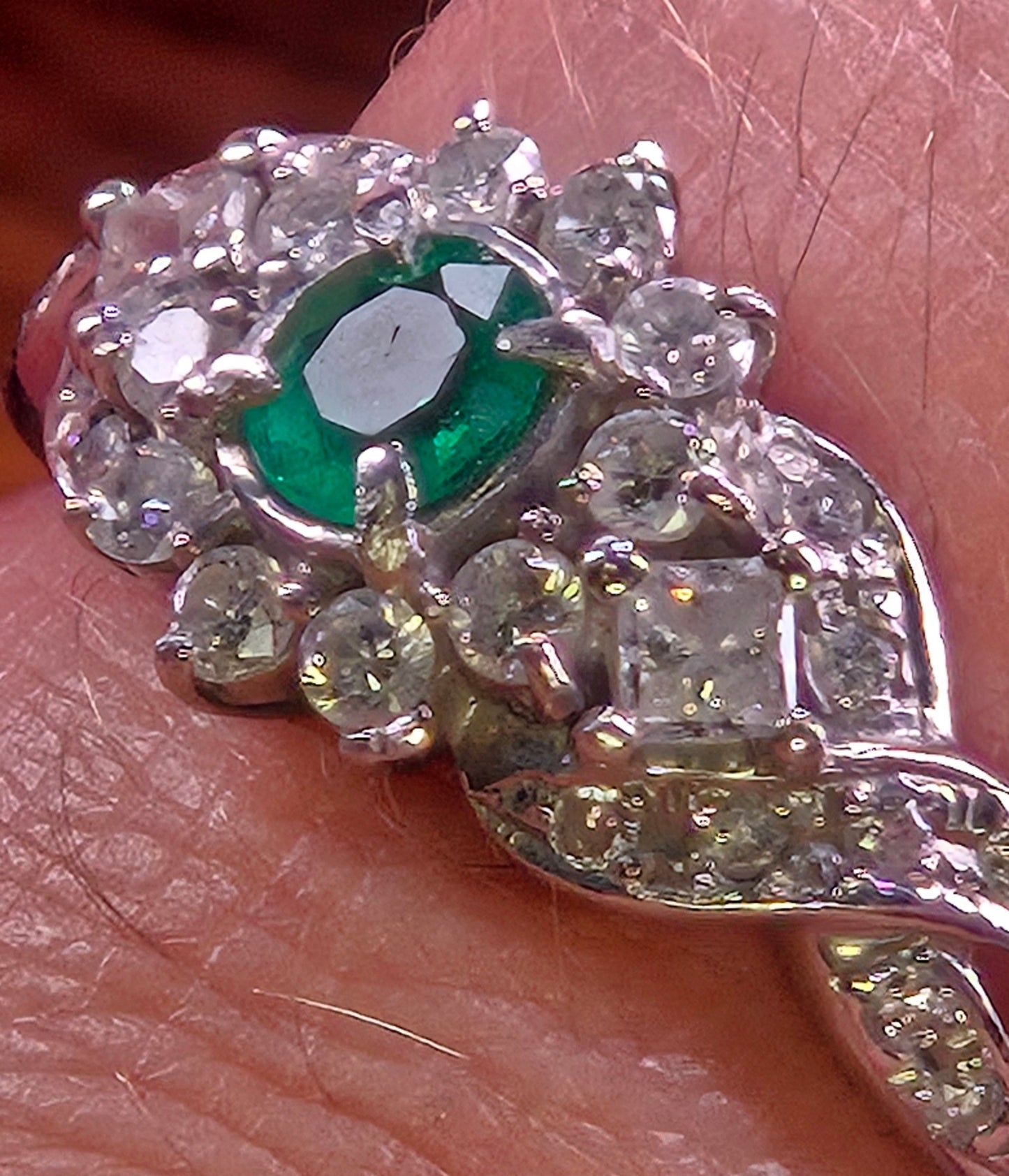 Angled shot of the Jardin Japonais ring on a finger, highlighting the brilliance of the diamonds against the deep green emerald.