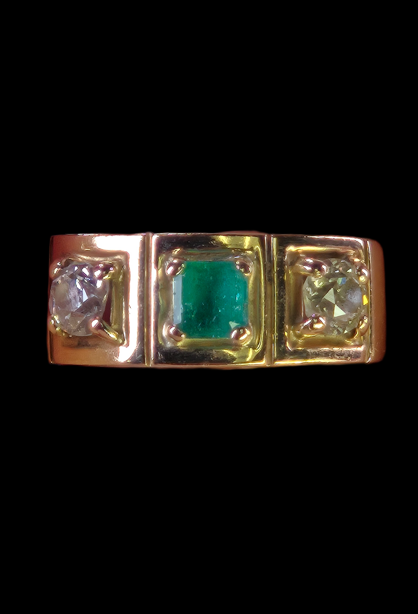 Studio photo of The Empress ring, featuring a square step-cut emerald flanked by two vintage diamonds in an 18K yellow gold setting.